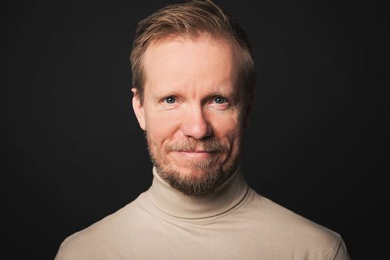 Matti Boustedt, smiling close-up headshot in beige turtleneck