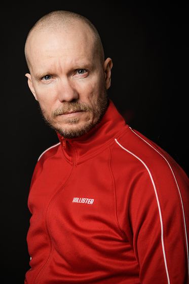 Matti Boustedt, character portrait looking over shoulder, shaved head, red jacket