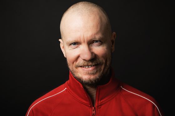 Matti Boustedt, smiling close-up headshot, shaved head, red jacket